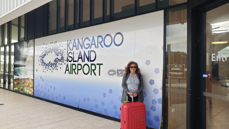 Cathy Laurenzi standing by the Kangaroo Island airport sign