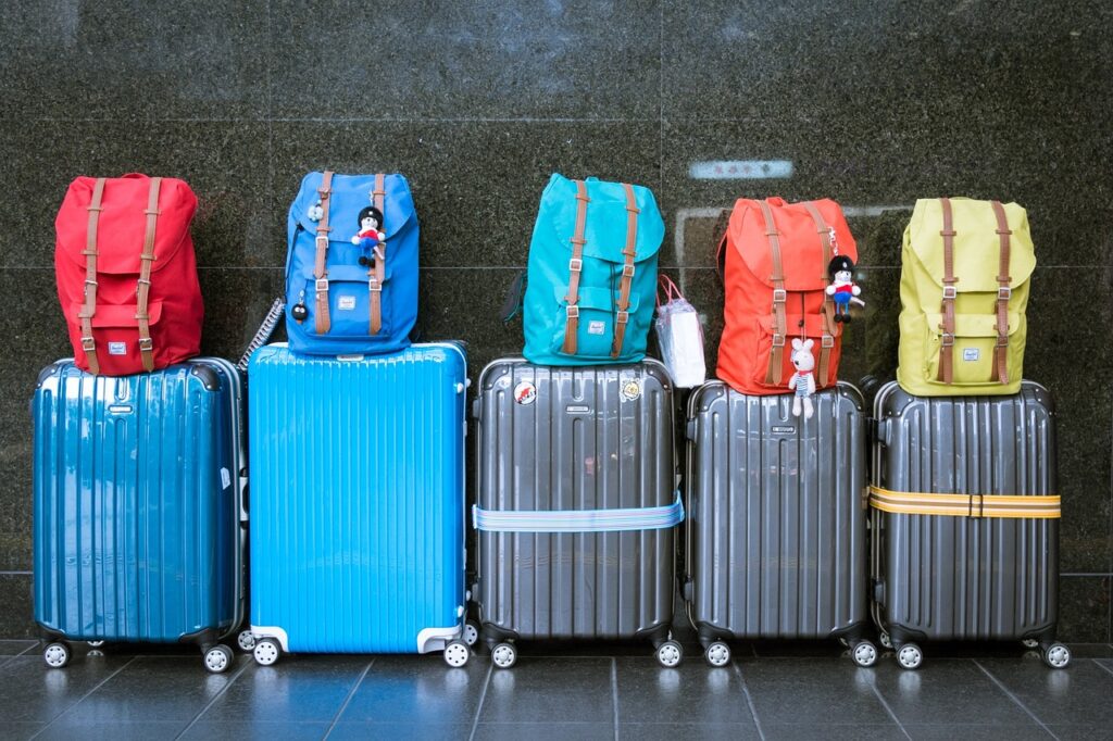 5 rolling suitcases with backpacks on top