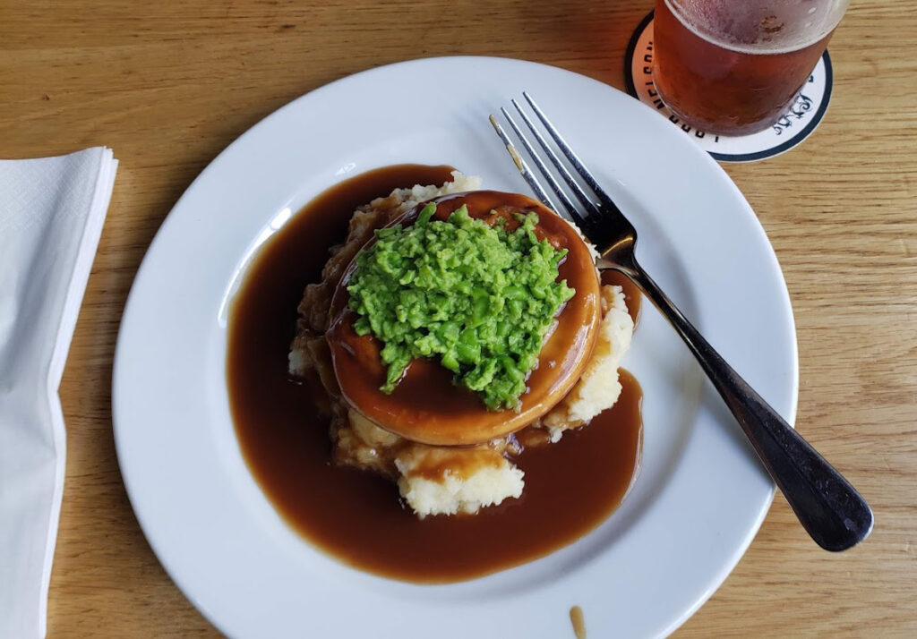 Meat pie with mashed potatoes, gravy and smashed peas.