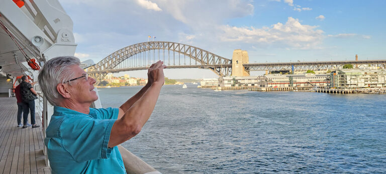 Man taking photos of Sydney Harbour from a cruise ship deck.