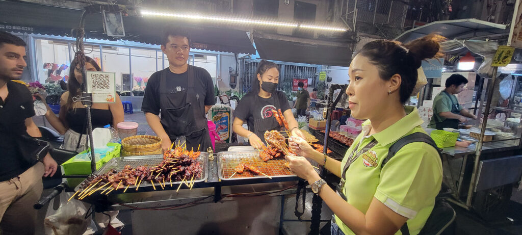 A food tour guide shows different skewers of meat.