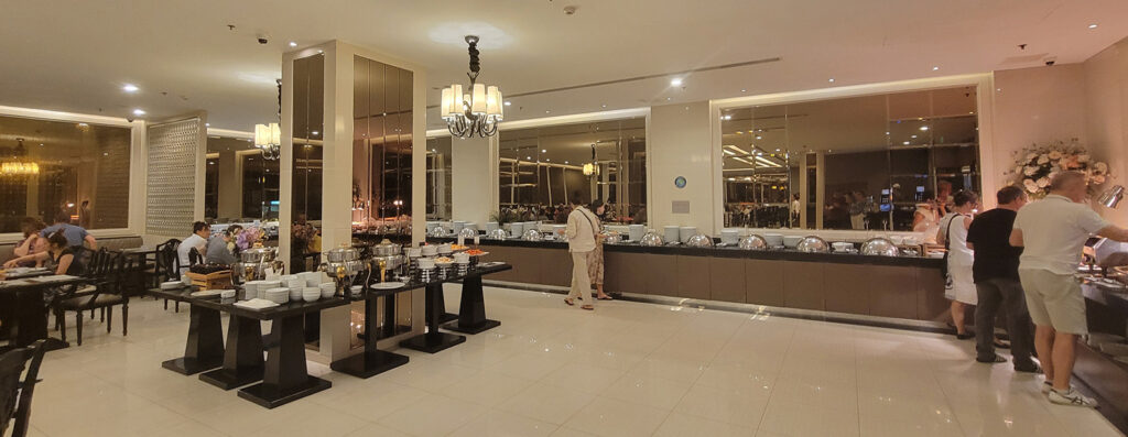 A big room with a long line of chafing dishes, plus an additional area in the middle with more food.