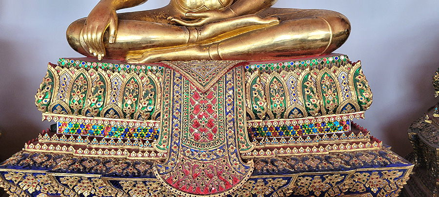 Detailed glass mosaic on the base of a buddha statue