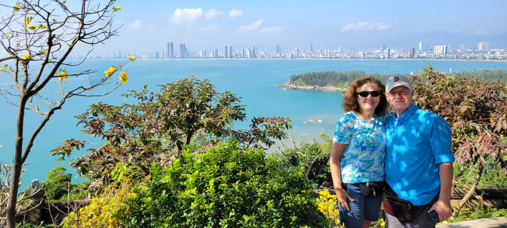 Cathy and Mark posing in front of a view of the bay and Ha Long city in the background.