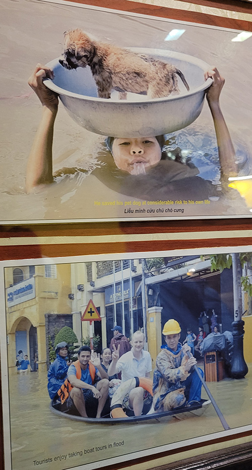 Two photos hanging on a wall - the top one is on up to her neck in flood waters holding a bowl over her head with a puppy in it. The second photo is of a group of people in a boat going through the flooded town of Hoi An, Vietnam.