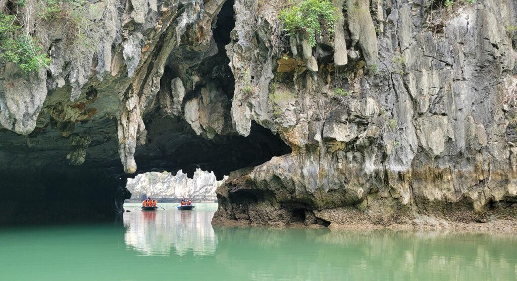 Two row boats entering a secluded cove in Ha Long Bay, Vietnam