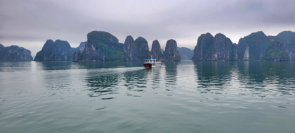 A boat traveling through rock formations in Halong Bay Vietnam