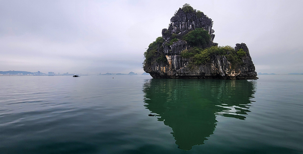 A lone rock formation and its reflection in Ha Long Bay