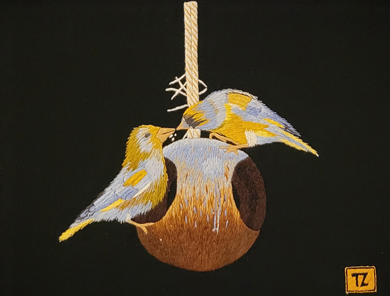 Needlepoint image of two birds on a feeder.