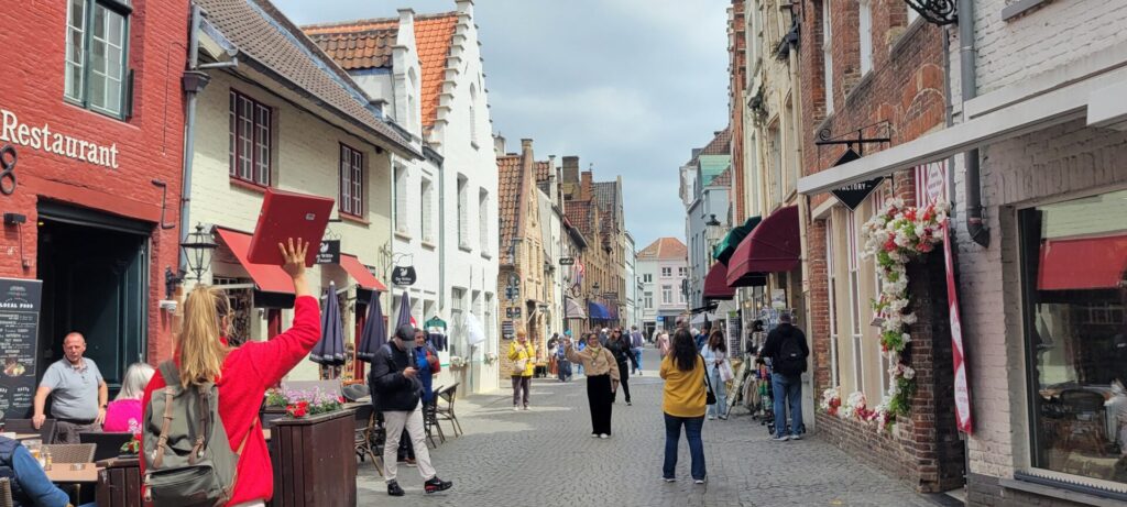 A tour guide leading holding a red book as she leads a group through the streets of Bruges, Belgium