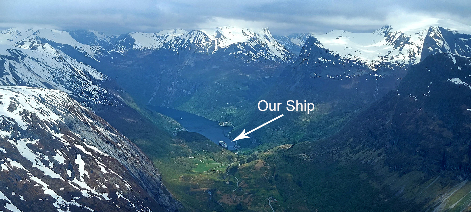View from Dalsnibba viewpoint with a cruise ship appearing very tiny below in Geirangerfjord.
