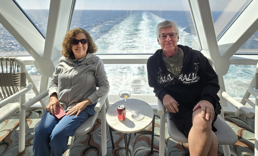 Cathy and Mark sitting inside in the back of the Apex with the ship's wake in the background.