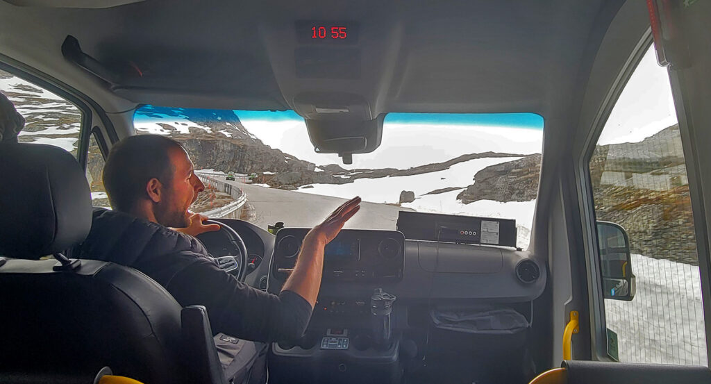 A man driving a van while he talks and waves his arms.