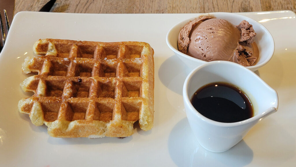 Belgian Waffle with chocolate ice cream and caramel syrup on the side.
