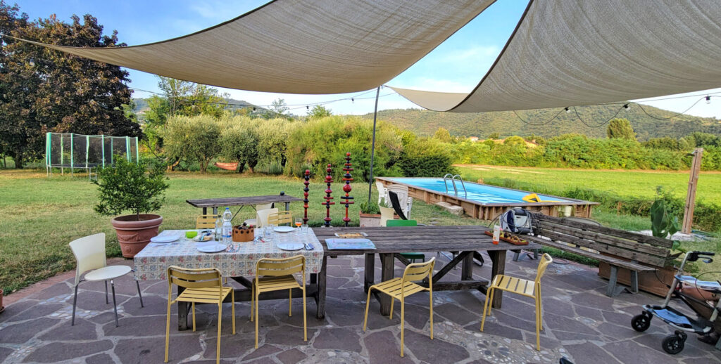 Long wooden table on a patio under large shade sails.