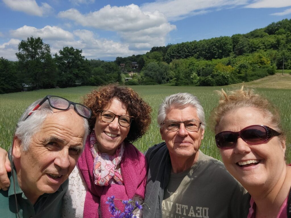 2 older couples taking a selfie with a green field behind them