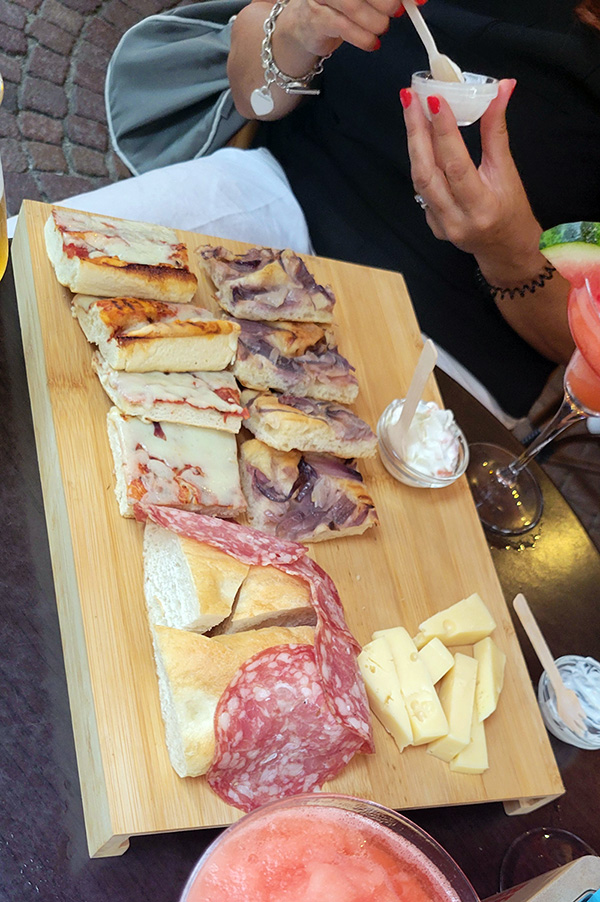 a wooden platter with focaccia, meat and cheese