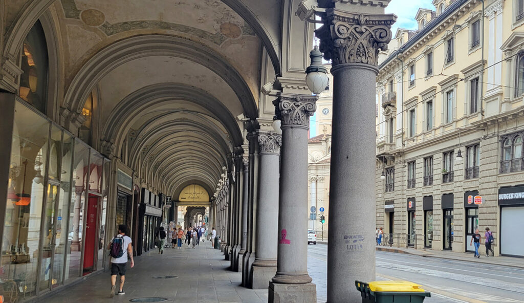 a sidewalk in Turin, Italy covered with a tall portico