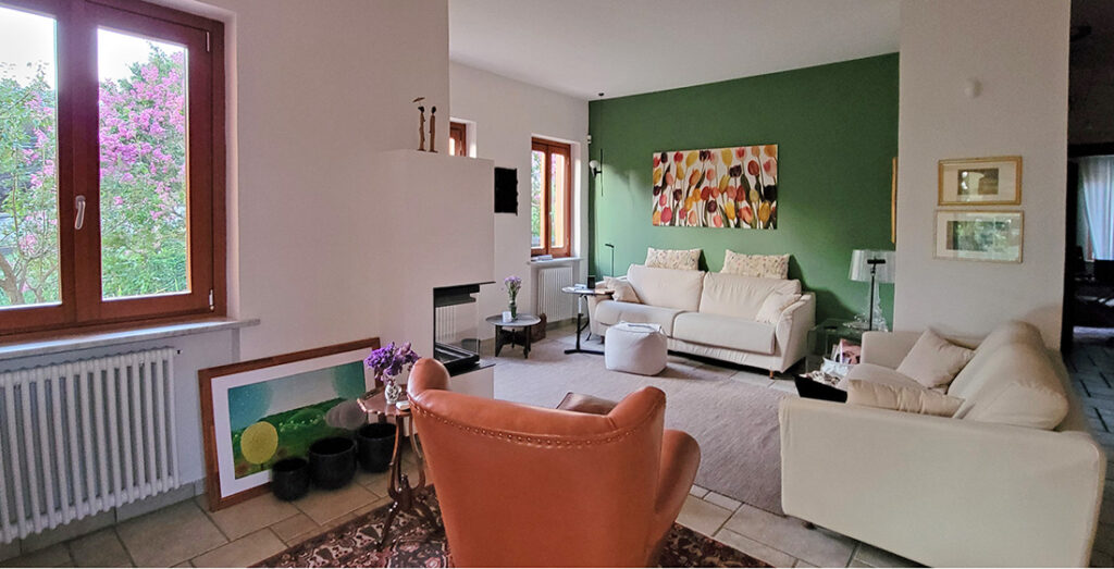 a living room with one dark green accent wall, two white love seats and one orange chair
