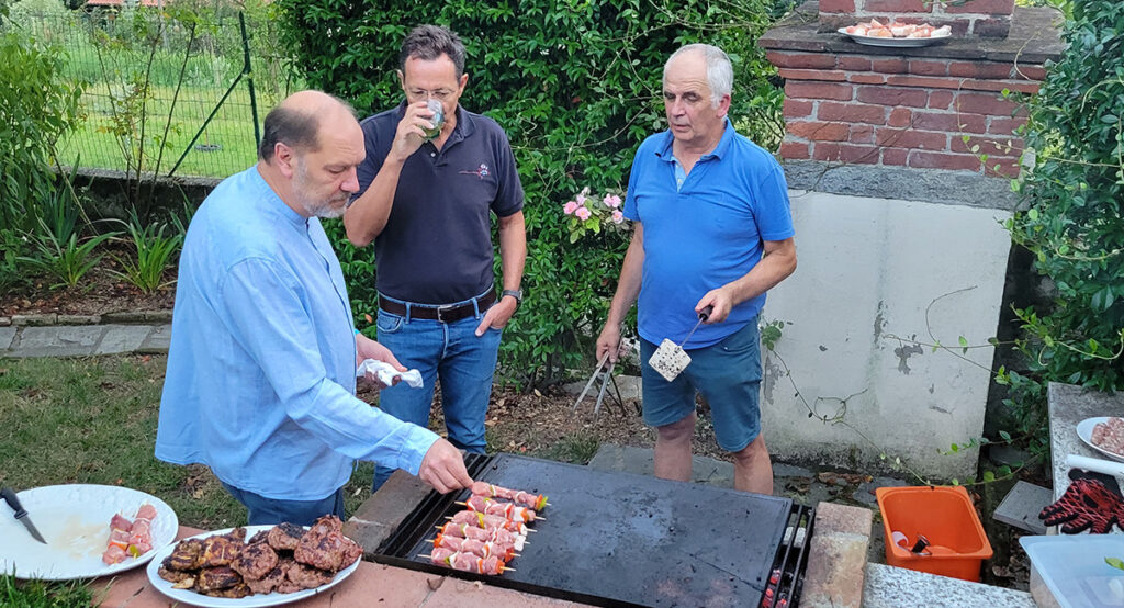 3 men standing around a grill