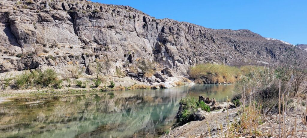 A scene on the Rio Grande River. A wall of rocks is on the far side.