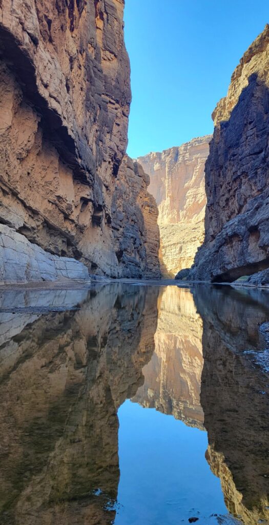 The sky reflecting in a river going through a steep, narrow canyon.