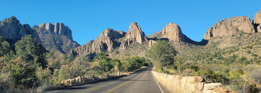 A road traveling through the desert with rocky peaks in the distance.