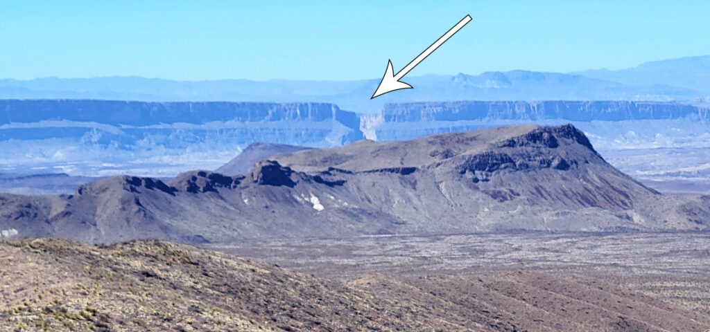 An arrow pointing to a notch in a distant mesa.